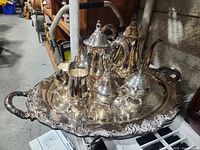 Full view of the silver tea set on a large ornate tray including two teapots, two sugar bowls, and two creamers