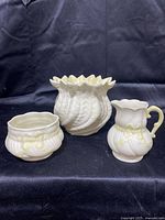 Front view of the Belleek trio including swirled shell vase, small bowl, and creamer with yellow ribbon decoration.