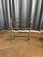 Front view of a vintage brass towel or quilt rack showing the structure and design.