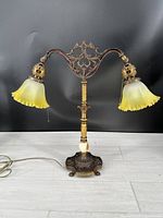 Full view of the two-light parlor lamp with frosted yellow shades and cast iron gold-toned arms