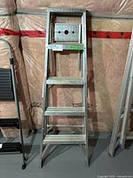 Front view of aluminum step ladder showing four steps and top platform with warning text