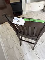 Top rear view of dark wood bar stool with label and size taped on top rail.