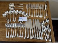 Full set of 45 pieces of Birks Regency Plate flatware displayed on wooden surface showing all types of utensils.