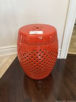 Full view of red ceramic garden stool showing detailed lattice cut-outs and glossy finish.