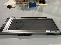 Treadmill folded on a concrete floor with power cord visible