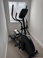 Overall side view of the elliptical machine showing its size and structure near a window