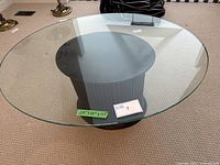 Top view of the oval transparent glass table top showing minimal wear and dimensions label.