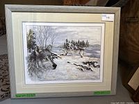 Framed print showing wolves in a winter landscape with snow and trees, signed and numbered 31/750.