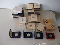 Overview of 28 coins in cases stacked on table