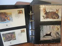 Open binder displaying plastic sleeves with first day covers showing wildlife illustrations, stamps, and WWF logos.
