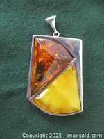 Front view of pendant showing two triangular amber panels in silver frame