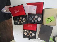Three open black hinged Royal Canadian Mint presentation cases showing complete sets of coins