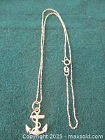 Full view of chain laid out with anchor pendant on green background