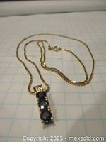 Chain and pendant laid on graph paper showing overall length and design