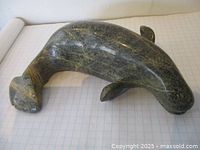 Side view of whale carving showing curved body and tail fluke