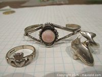 Photo showing all three sterling silver pieces on grid paper background: Navaho bracelet with pinkish white stone, killer whale ring, and Claddagh heart crowned hands ring.