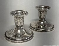 Pair of round base sterling silver candle holders showing slight surface wear and the polished finish.