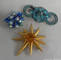 Top view of three vintage rhinestone brooches showing overall condition and color detail