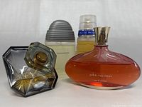 Four assorted vintage used perfume bottles including John Varvatos, Pure One Chris Adams, Lancôme, and one unidentified bottle.