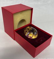 Clear Baccarat crystal egg with gold floral design sitting in original red Baccarat presentation box with foam and velvet lining.
