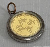 Obverse side showing Chinese characters on the gold coin within metal bezel with loop