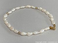 Freshwater pearl bracelet shown laid flat displaying the pearls and gold beads.