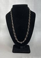Necklace displayed on black bust to show full length and chain links
