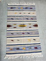 Full view of Southwestern tribal handwoven kilim rug laid flat showing pattern and fringe edges.