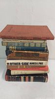 Stacked view of ten vintage/antique books from various authors and titles, showing mostly spines and some covers with wear and aging.