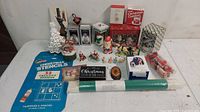 Lot showing multiple assorted Christmas holiday decorations and craft items including stencils, ceramic tree, figurines, and boxed collectibles.
