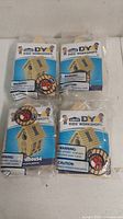 Four individually packaged DIY bird house building kits with visible front packaging showing brand, logo, and birdhouse image.
