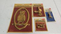 Lot of 4 new old stock solid brass decorations in original sealed packaging including owl and ship wheel door knockers, brass bird, and cork screw.