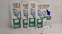 Four new and unopened Cat House Hideaway packages standing upright, showing front branding and illustrations.