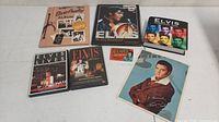 Overview photo showing all Elvis Presley items including album binder, DVDs, bubble gum card, and picture