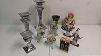 Overview photo showing three Lenox silver candlesticks, Hindu Ganesh idol, two patriotic figurines, ceramic candle holder, metal plant stands, and small honey crate.