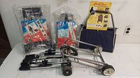 Three luggage carts and carriers, two sealed new foldable carts and one used navy fabric cart