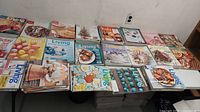 Photo showing many Martha Stewart Living magazines arranged across a table, revealing colorful covers with various themes and subjects related to lifestyle, cooking, and crafts.