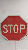 Front view of the metal stop sign showing red background with white STOP text and two mounting holes.