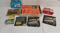 Wide view of the lot showing multiple boxes of staples, staplers in packaging, and a large blue box.