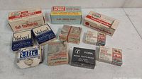 Multiple assorted vintage toothpick boxes arranged on a surface showing brand names and packaging styles.