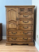 Front view of solid wood chest dresser with six drawers and one door, metal handles, and chestnut finish.