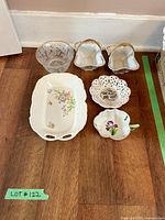 Top view of six candy dishes and bowls arranged on wooden floor, showing floral and gold detailing.