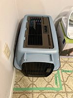 Top front view of the Petmate kennel showing blue top, black bottom, and front black metal wire door.