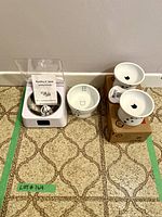 Photo of motion sensor cat feeder with stainless steel bowl, instruction manual, USB charging cable, one ceramic water bowl and two ceramic raised cat food bowls.