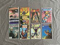 Full view of 12 comics laid out showing covers of Transmetropolitan, GrimJack, Crossfire, DV8, Barabbas