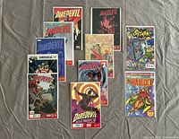 Twelve Marvel comic books laid out on a gray surface. Includes several Daredevil issues, one Batman comic, and a Warlock comic.