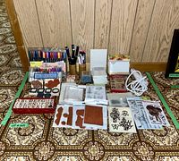 Overview of all items including markers, stamps, acrylic blocks, heat tool with white cord, and stamp pads arranged on patterned floor.