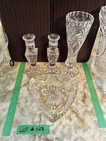 Photo showing the crystal vase, two candle holders, and a triangular crystal ashtray on a table with a light patterned surface.