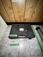 Closed black plastic carrying case for weights and barbells on floor.