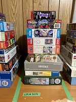 Stack of nine different puzzle boxes with visible brands Ravensburger, Cobble Hill, Buffalo Games and piece counts ranging from 300 to 1000 pieces.